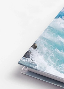 Shop photo books by cover: A close-up of a layflat photo book with a cover photo of ocean waves.