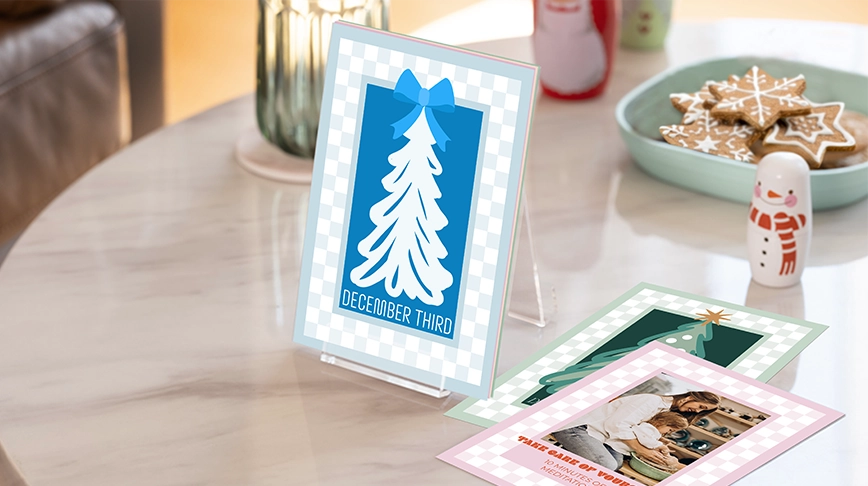 Photo Calendars by Occasion: Several 5x7 Advent Calendar cards on a marble table, with the card in the foreground showing a blue Christmas tree design