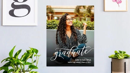 Large Prints: A large graduation portrait print of a young woman hanging on a wall in a decorated room with plants.