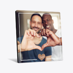 Desk Art: A square desk art print of a couple making a heart shape with their hands, framed by a white border.