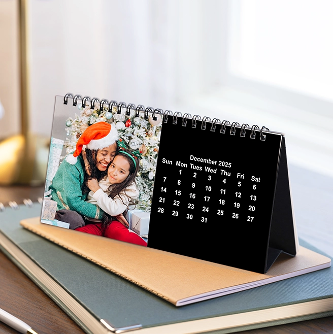 Photo Desk calendar, 4x8: A 4x8 desktop photo calendar for December 2025, showing a photo of a mother and daughter embracing in Santa hats next to a Christmas tree.