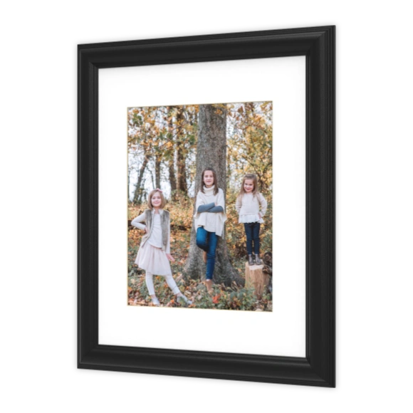 Framed Prints: A photo of three girls posing outdoors, presented in a black frame with a white matboard, shown at an angle.